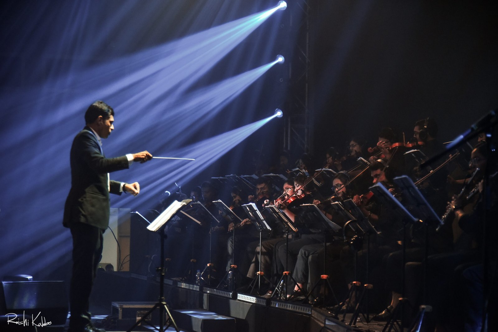 Shariful Islam conducting the Dhaka Symphony Orchestra under stage lights